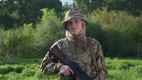 Portrait of Female Soldier in Camouflage Uniform Looking at Camera alt