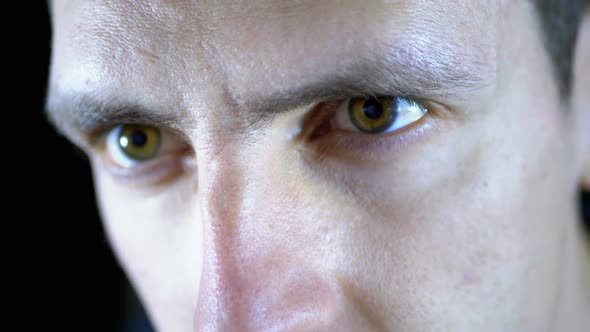 Close-up of the Eyes and Face of a Young Man Working at a Computer on a Black Background alt