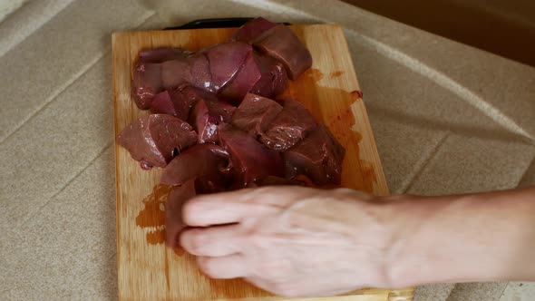 Closeup of Cutting a Pork Liver with a Knife on a Kitchen Board
