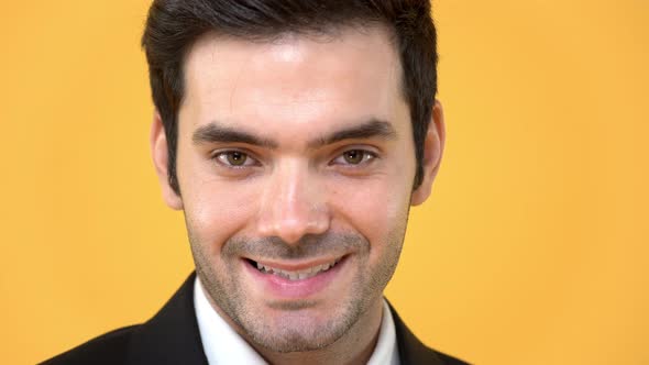 Close up of handsome friendly man face smiling on isolated yellow studio background