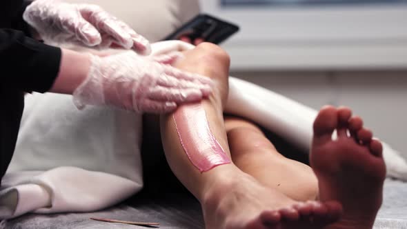 Waxing Master Ripping Off the Wax of Her Woman Client's Leg alt