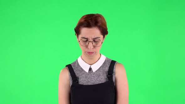 Portrait of Funny Girl in Round Glasses Is Very Offended and Looking Away Then Smiling . Green alt