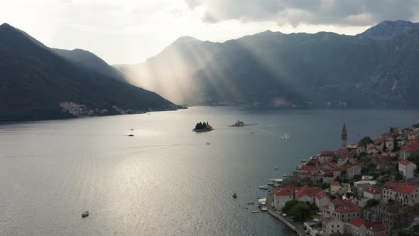 Mediterranean sun peeking through clouds over Boka Kotor Bay in Perast Montenegro. alt