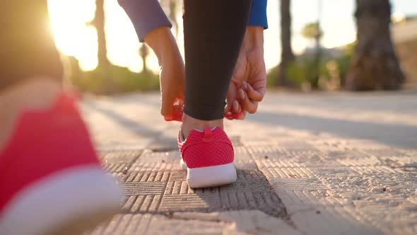 Close Up of Woman Tying Shoe Laces and Running Along the Palm Avenue at Sunset alt