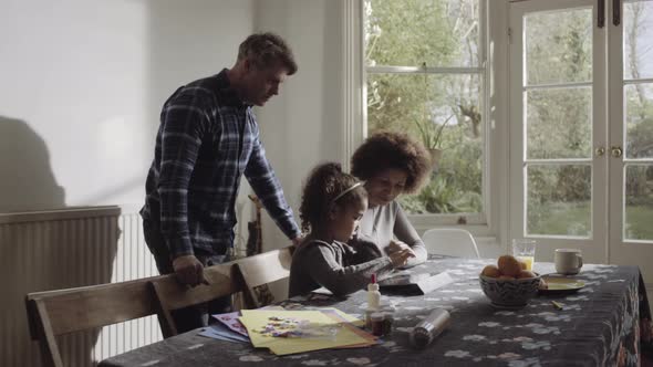 Parents with daughter on digital tablet on table in living room