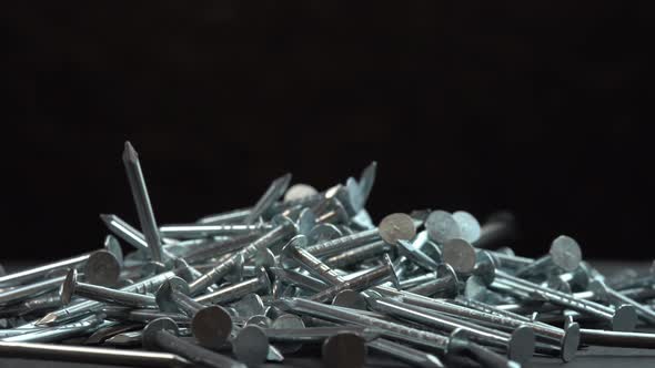 Metal Steel Nails for Construction Work Falling on a Rotating Surface on a Black Background Hobnails alt