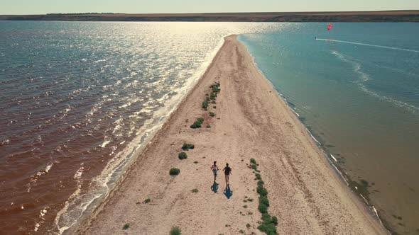 Man and Woman Running By Sand Beach Between Water San Dbar at Mykolaiv Region Ukraine alt