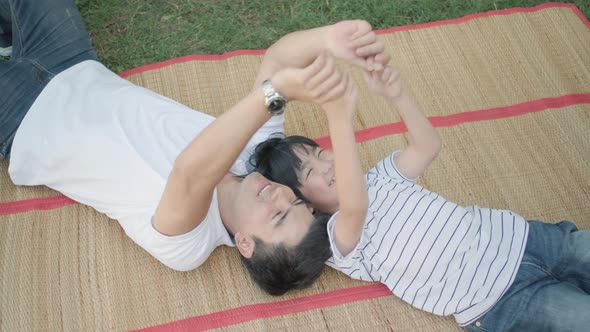 Father and son play together by lie on mat in home garden and they look happy