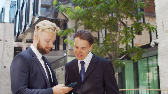 Confident businessman and his colleague in front of modern office building. alt