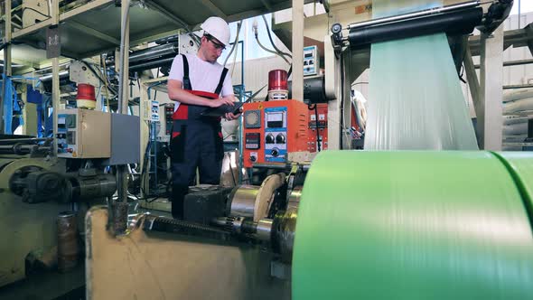Factory Machine Is Producing Polyethylene Foil Under Worker's Control alt