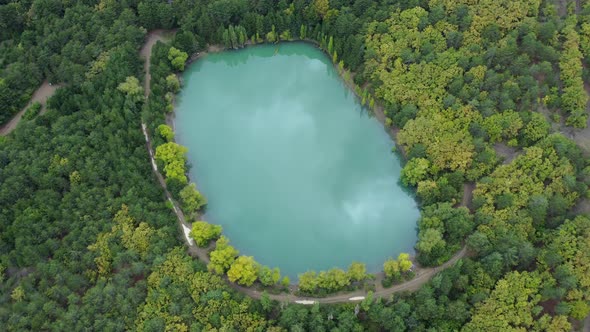 Aerial view over a turquoise lake, with a reflection of the passing clouds
