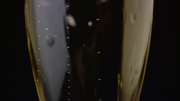 Bubbles of a Sparkling Drink Rise Up the Glass. Black Background. Close Up alt