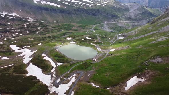 Drone shot (rotating) of a Ski Resort in the Summer with a Water Reserve and Patches of Snow alt