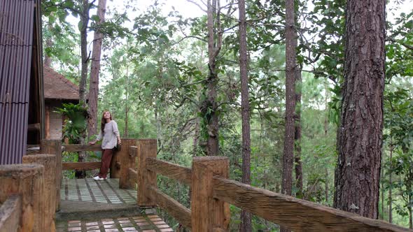 A young woman standing in front of a log cabin in the woods