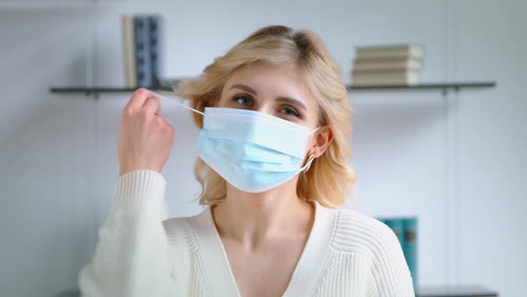Young woman taking off medical mask and smiling while looking at camera alt
