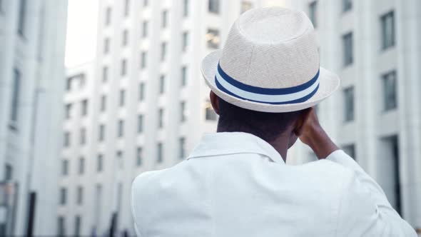 Black man tourist in suit films panorama of local highrise office buildings alt