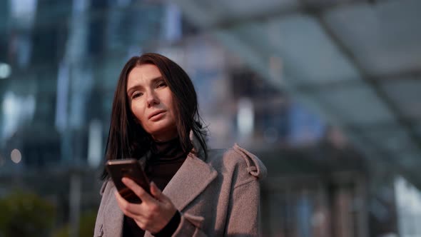 Adult Woman is Calling By Cellphone Walking in City in Fall Day Portrait alt