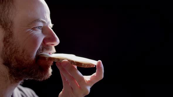 BACKLIT STUDIO BLACK - A man eats a cheese sandwich alt