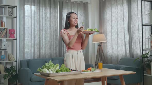 Asian Woman Eating Healthy Food Before Smiling And Showing Thumbs Up Gesture To Camera At Home alt