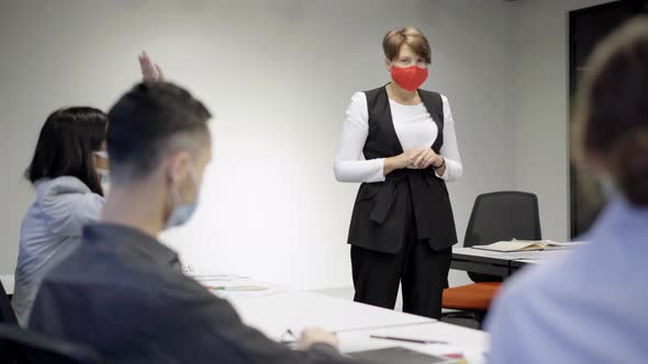 Positive Confident Woman in Covid19 Face Mask Discussing Business Project with Coworkers in Office alt
