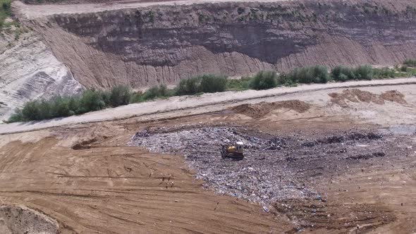Birds Fly Aroud Garbage Pile on Junkyard Near Working Excavator