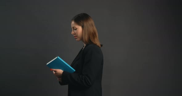 Business Woman in Suit is Opening Her Notepad Office Working Lady Searches Notes in Paper Notepad