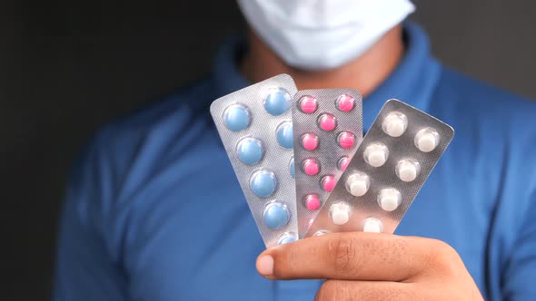 Young Man in Protective Mask Hand Holding Blister Packs alt