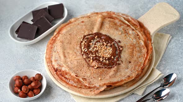 Pancakes with chocolate and nuts. Pouring chocolate on pancakes. Maslenitsa, blini