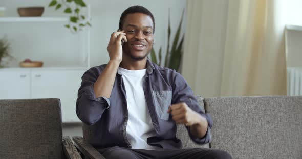 Afro Student Learns Good News on Phone Enjoys Sitting at Home. Black Male Businessman Freelancer alt
