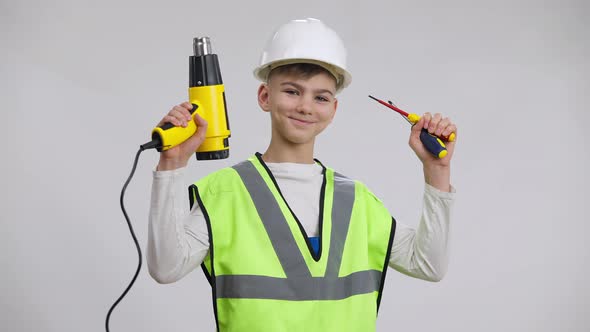 Cute Caucasian Boy in Hard Hat Raising Tools Smiling Posing at White Background alt