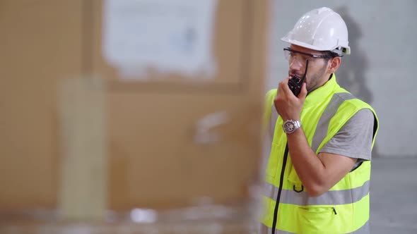 Professional Cargo Worker Talks on Portable Radio to Contact Another Worker alt