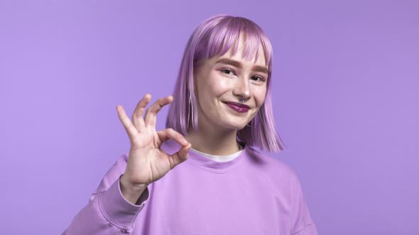 Young Woman Showing Ok Like Sign Over Violet Studio Background alt