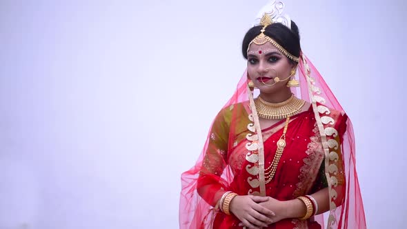 Isolated Indian Bengali bride wearing red saree smiles against white background alt