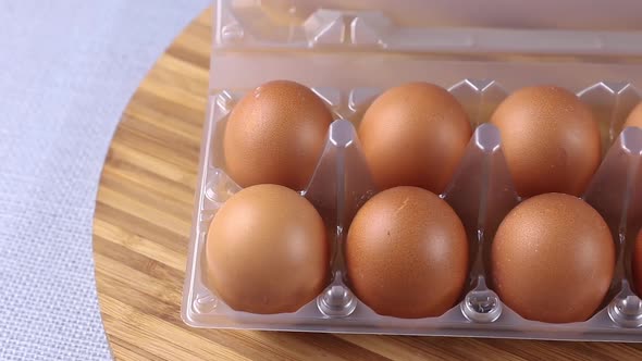 fresh yellow eggs in a plastic box close-up on a wooden cutting board