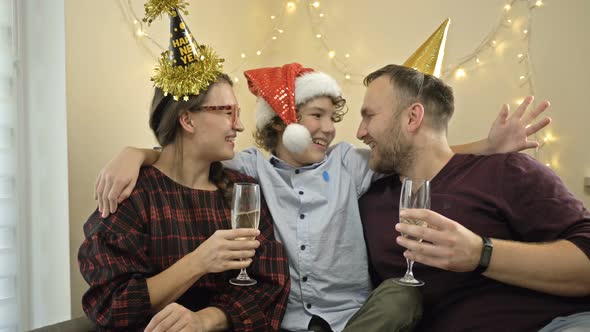 Friendly Family of Three Is Celebrating New Year or Christmas. Parents Are Drinking Champagne. alt