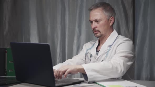 Mature Doctor Spending Day at Work in Office
