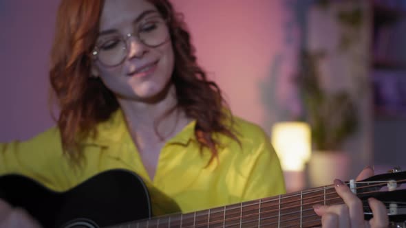 Girl with Love in Her Heart Plays Guitar and Enjoys Music While Relaxing at Home in Evening Smiling alt