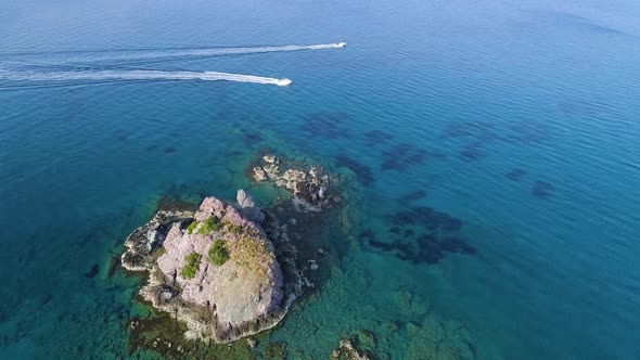 Yachts in the Water A Lonely Rocky Peak in the Open Sea Aerial Top View Drone  Shot alt