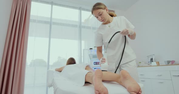 Woman is Receiving the Vacuum Massage Her Legs and Buttocks with Tool While Lying in the Spa Salon alt
