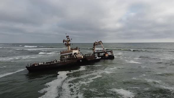 Drone footage of an old rusty sunken ship with lots of seagulls on it alt