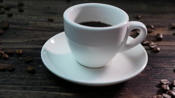 Aromatic Coffee In A Cup In Slow Motion, Espresso On A Wooden Background, Roasted Coffee Beans