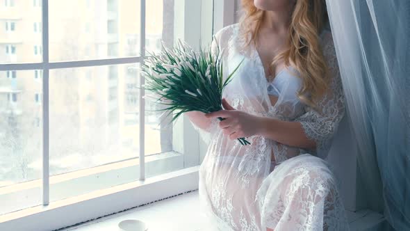 Unrecognizable Young Slim Sexy Blond Girl in Lingerie and Boudoir Sitting in Windowsill in Winter