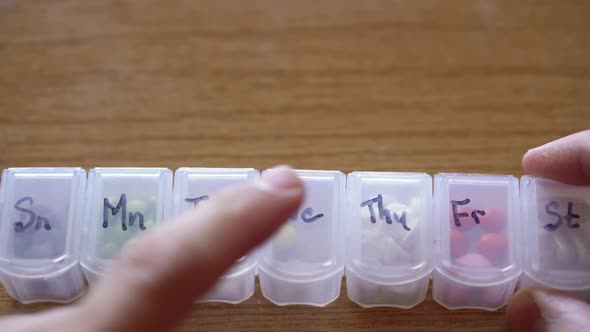 Extreme Close Up of Male Hands Fingers Taking Pills From Plastic Organizer Box