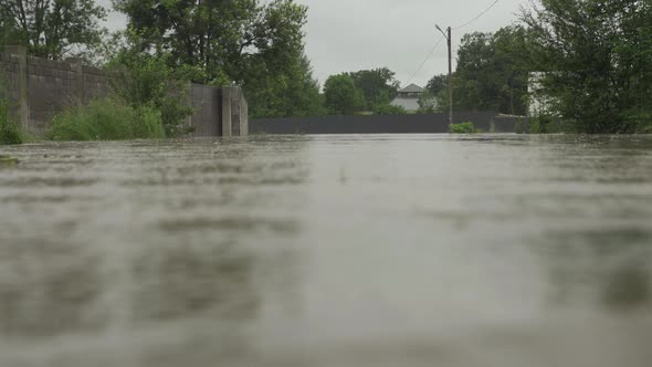 Flooded Street During Floods. Water Flooded the Road and the Fence of a Private House. It Rains and