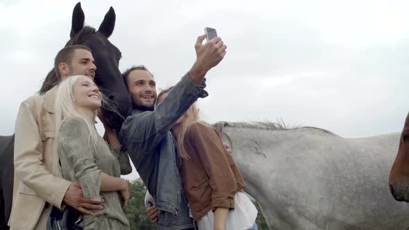 Young Man and Woman Friends Make a Selfie with White and Black Horses Outdoor Gimbal Steadicam Slow