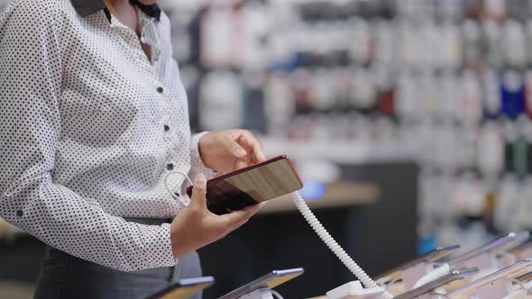 Woman is Choosing Cell Phone Viewing Exhibition Samples in Digital Equipment Store Lady is Buying alt