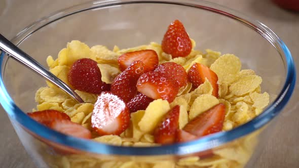 Sliced Strawberries Fall Into a Bowl with Cornflakes alt