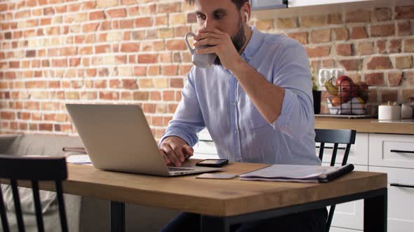 Video of man in a shirt sitting and working in the kitchen. Shot with RED helium camera in 8K. alt