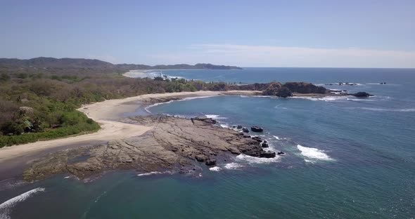 Aerial drone view of the beach, rocks and tide pools in Playa Palada, Guiones, Nosara, Costa Rica. alt