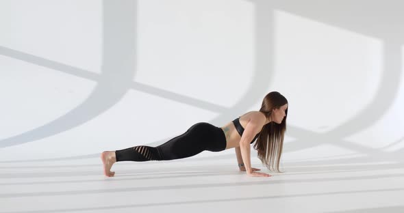 Side View of Young European Woman Working Out Doing Pushups on a White Sunny Background